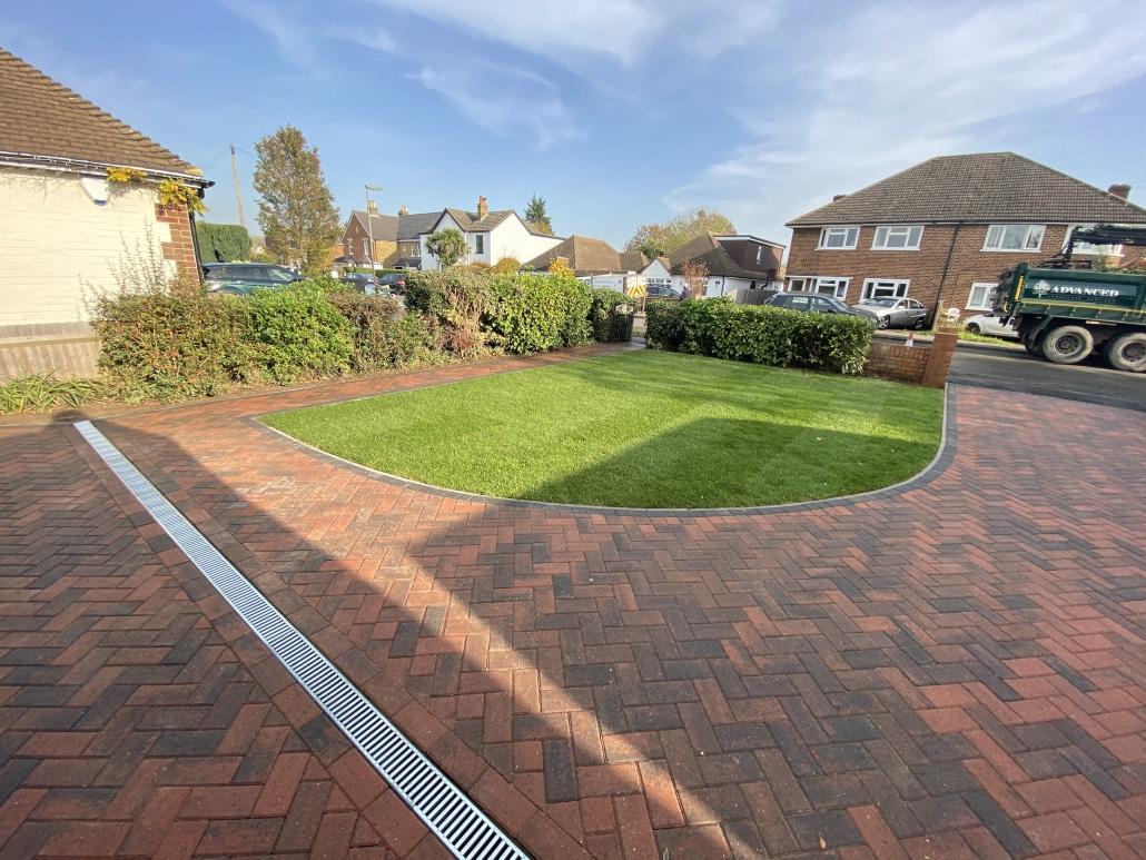 Red block paved driveway shaped around a front lawn