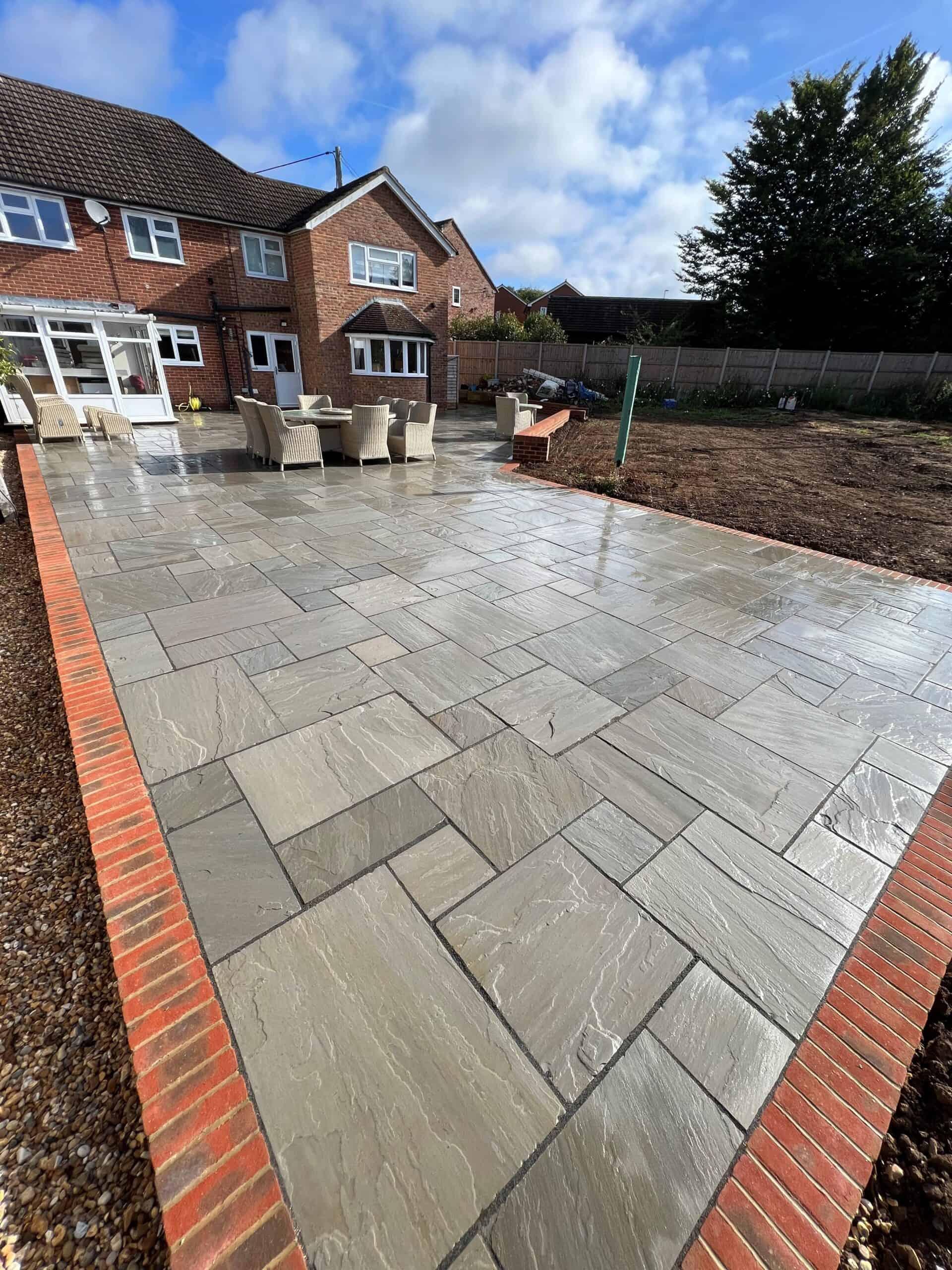 Large sandstone entertaining patio with brick edging