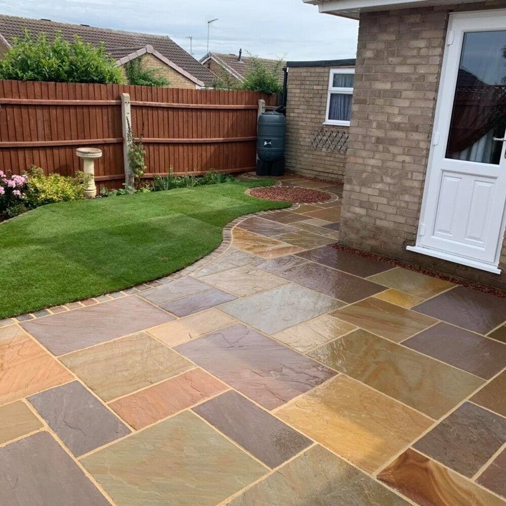 Natural stone patio and landscaped lawn by Harcourt Exteriors