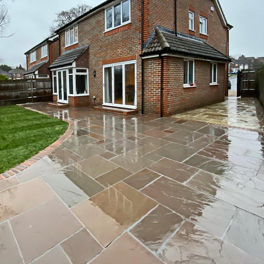 Wraparound natural sandstone patio and lawn by Harcourt Exteriors